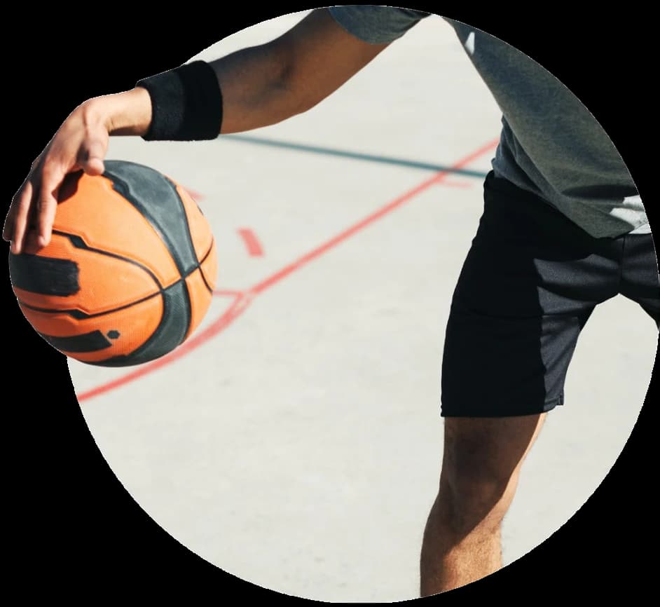 A basketball player holding a ball on an outdoor court.